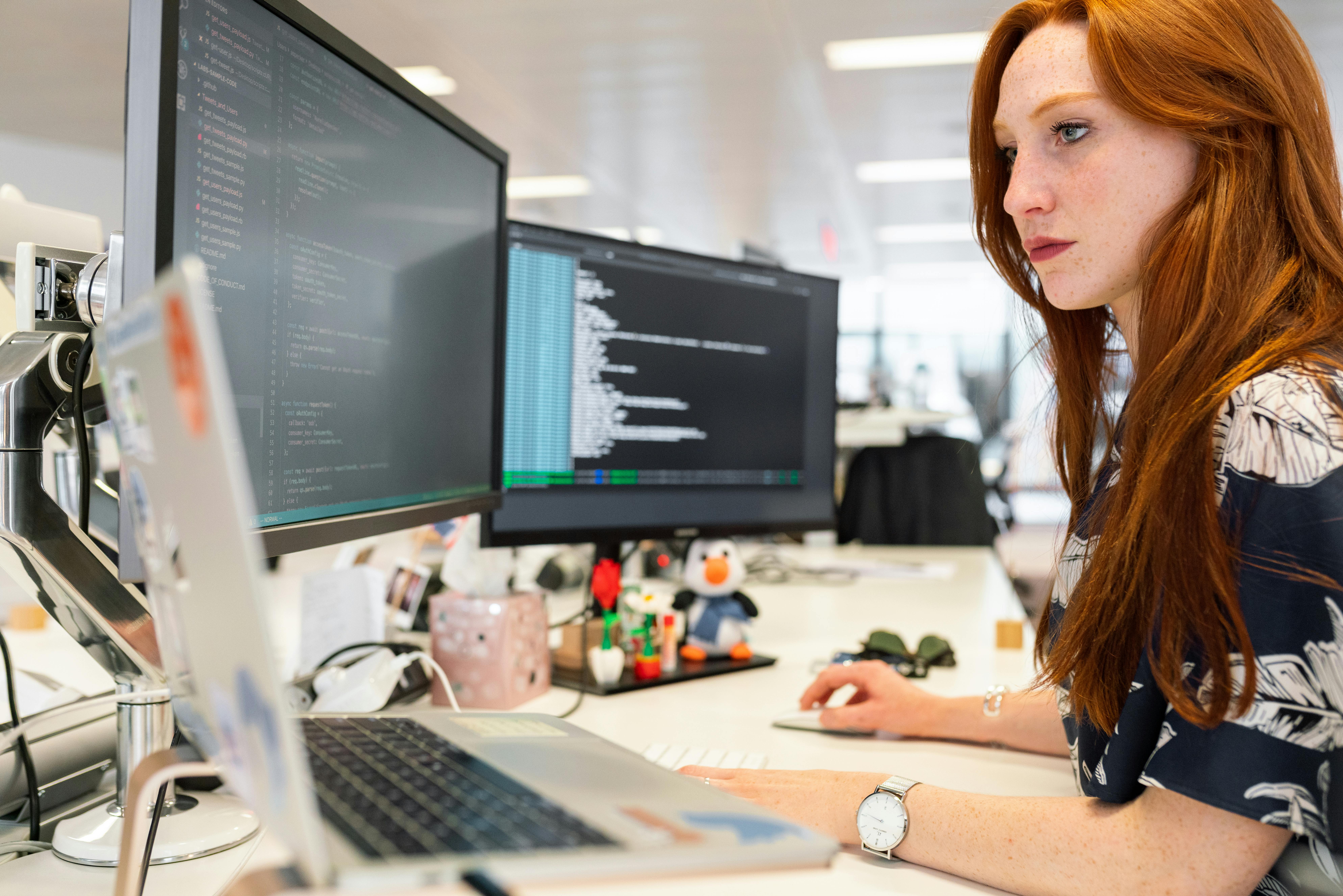 Person programming on computer with multiple monitors