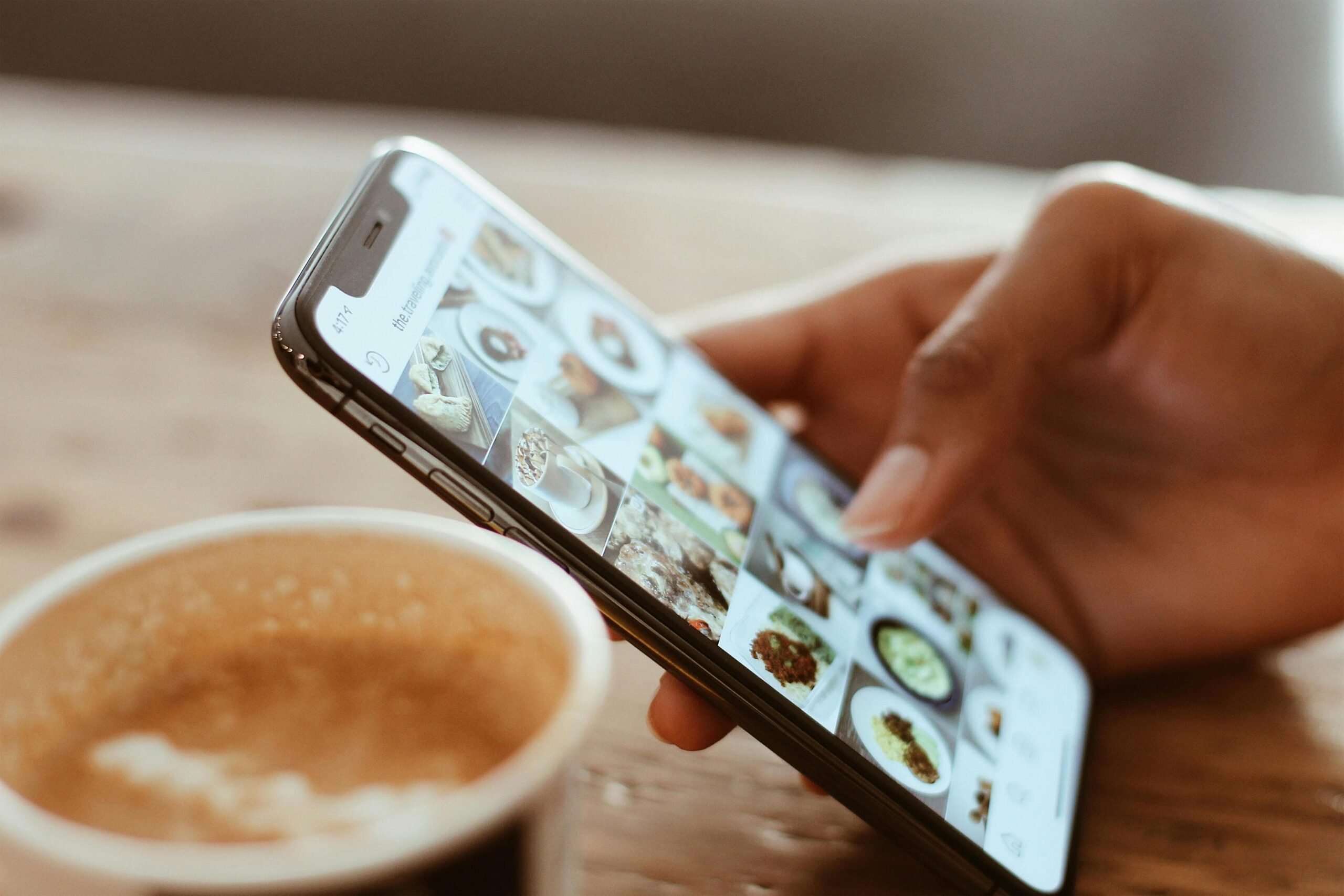Hospitality industry influencer reviewing photos of food next to coffee cup